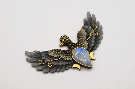 Decorative brooch with eagle design and gemstone on a white background