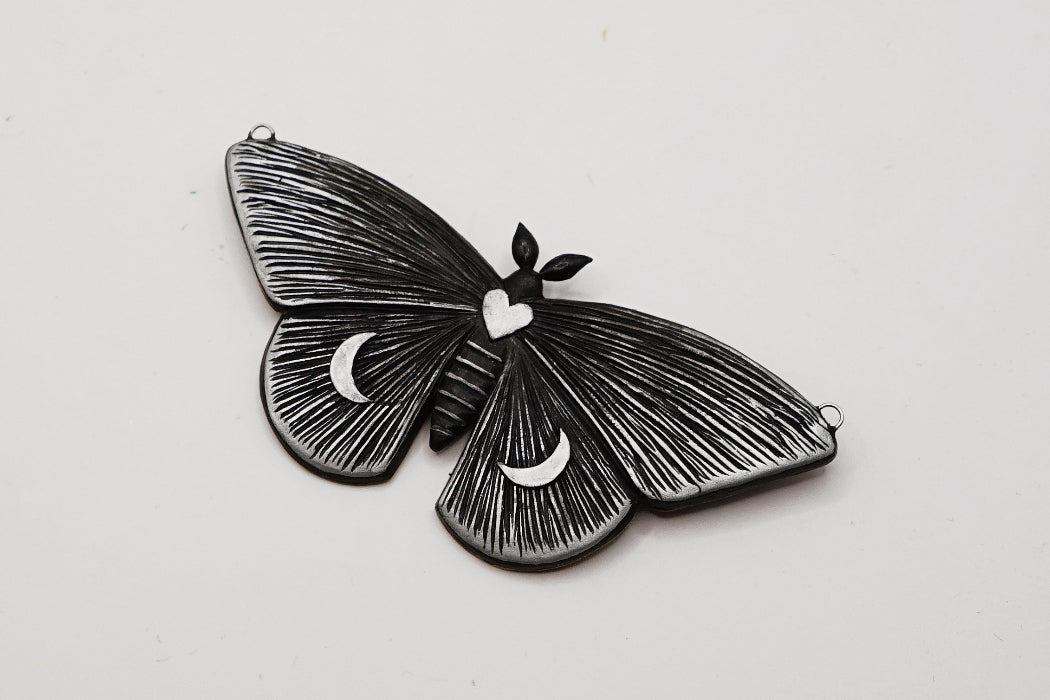 Black butterfly-shaped pendant on a light gray background