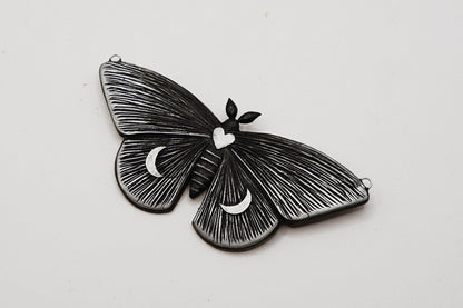 Black butterfly-shaped pendant on a light gray background