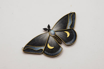 Moth-shaped brooch with gold accents on a white background