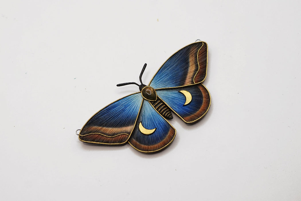 Decorative butterfly ornament with blue and gold details on a white background