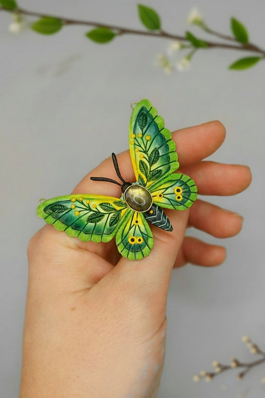 Hand holding a green and yellow butterfly-shaped object against a gray background