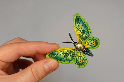 Hand holding a green and yellow butterfly-shaped object against a gray background