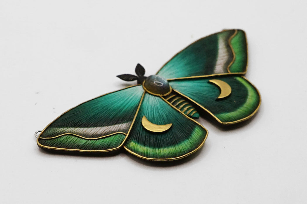 Decorative green moth pendant on a white background