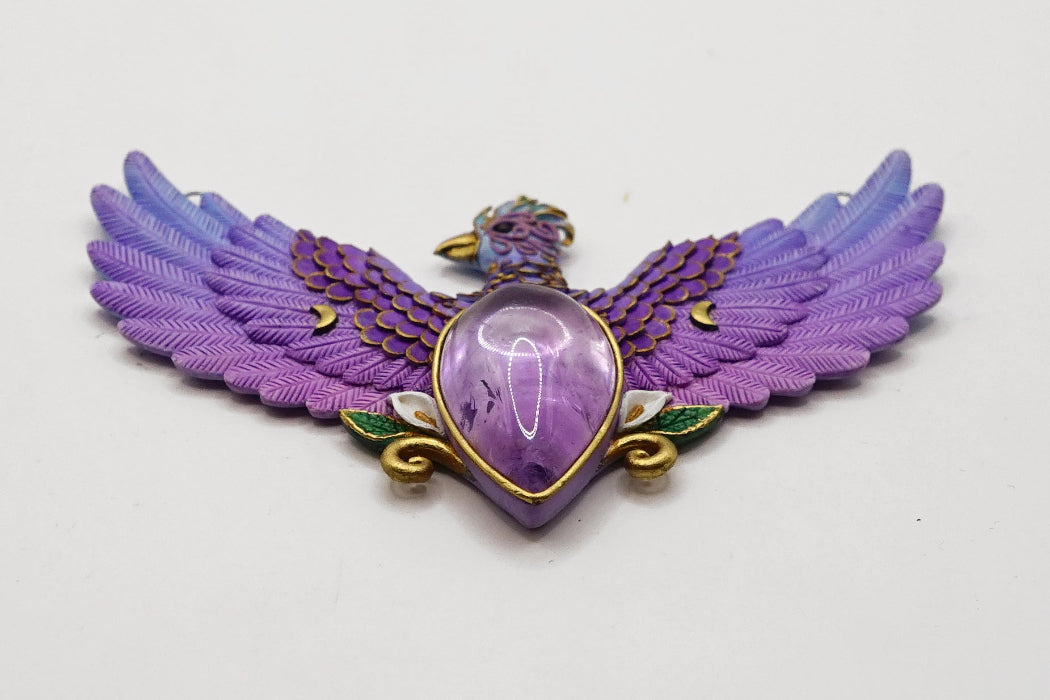 Purple winged pendant with a central gemstone on a light gray background