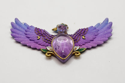 Purple winged pendant with a central gemstone on a light gray background