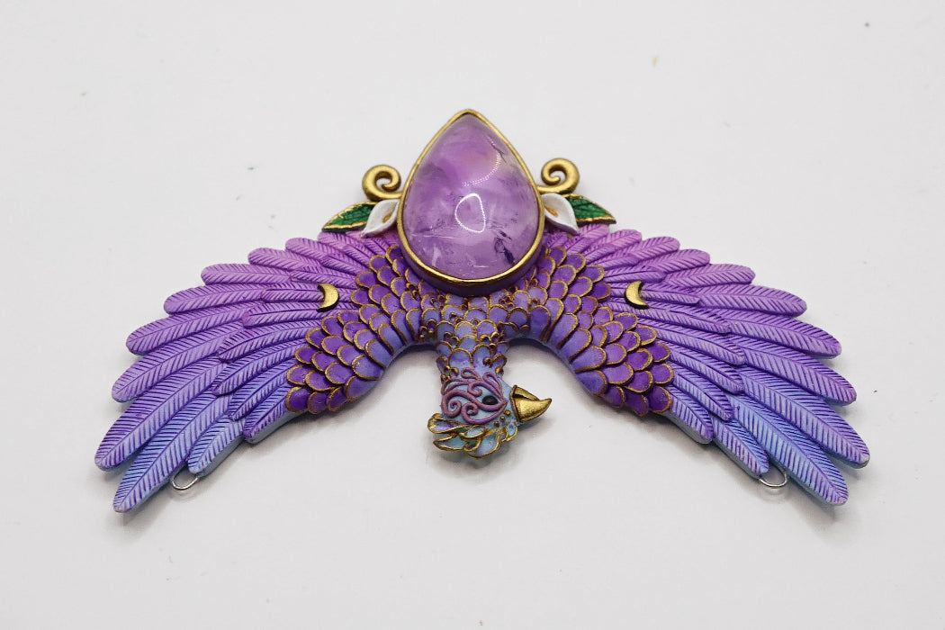 Purple phoenix pendant with a central gemstone on a white background