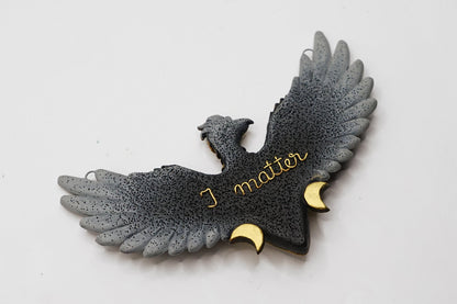 Eagle-shaped pendant with 'I matter' text on a light gray background