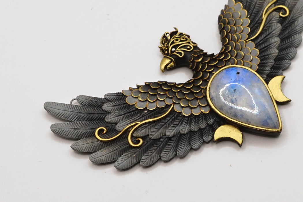 Decorative bird-shaped pendant with gold and black details on a white background
