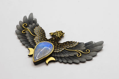 Decorative brooch with eagle design and blue stone on a light gray background