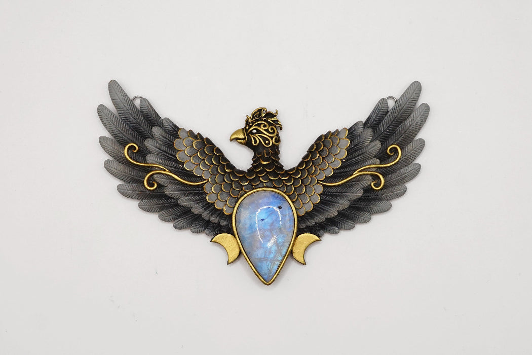 Decorative brooch with eagle design and gemstone center on a white background