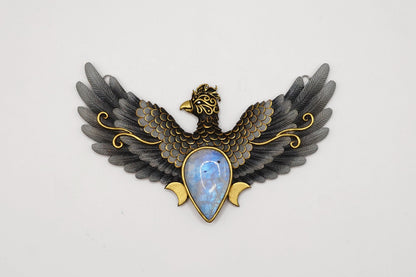 Decorative brooch with eagle design and gemstone center on a white background