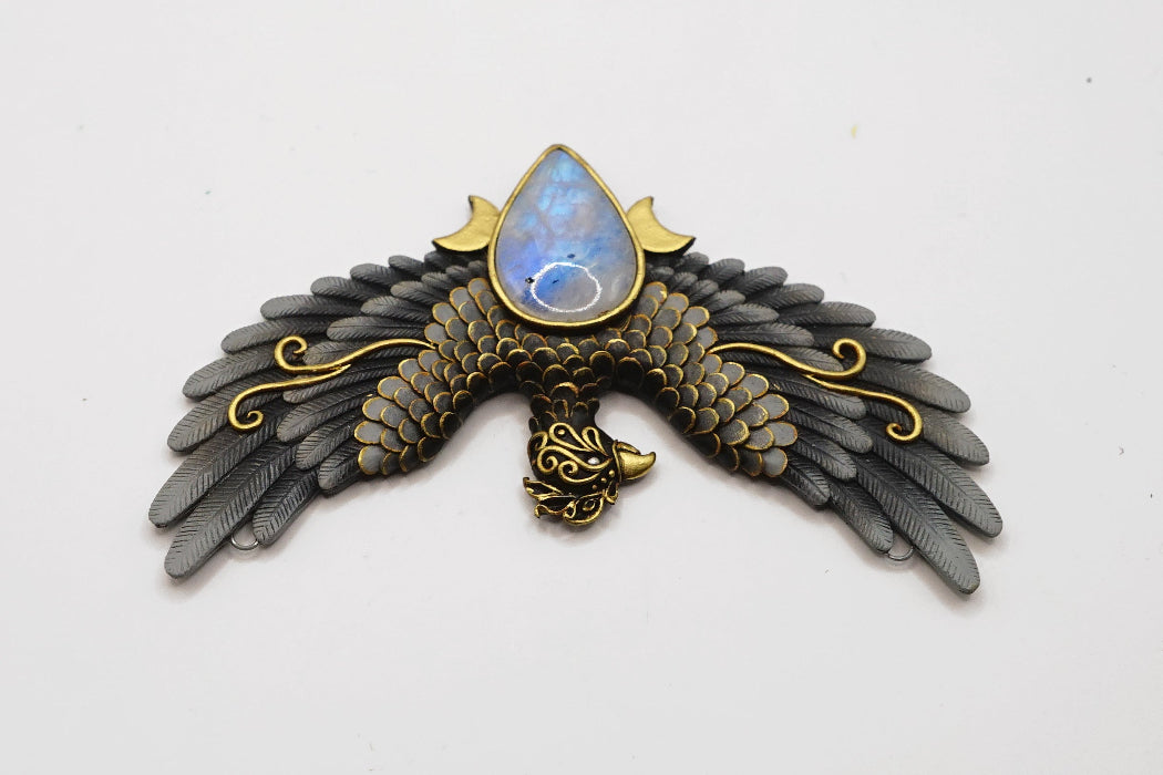 Decorative brooch with eagle design and central gemstone on a white background