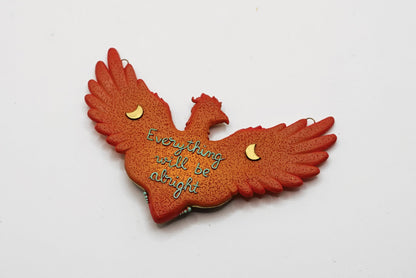 Red phoenix-shaped ornament with 'Everything will be alright' text on a white background