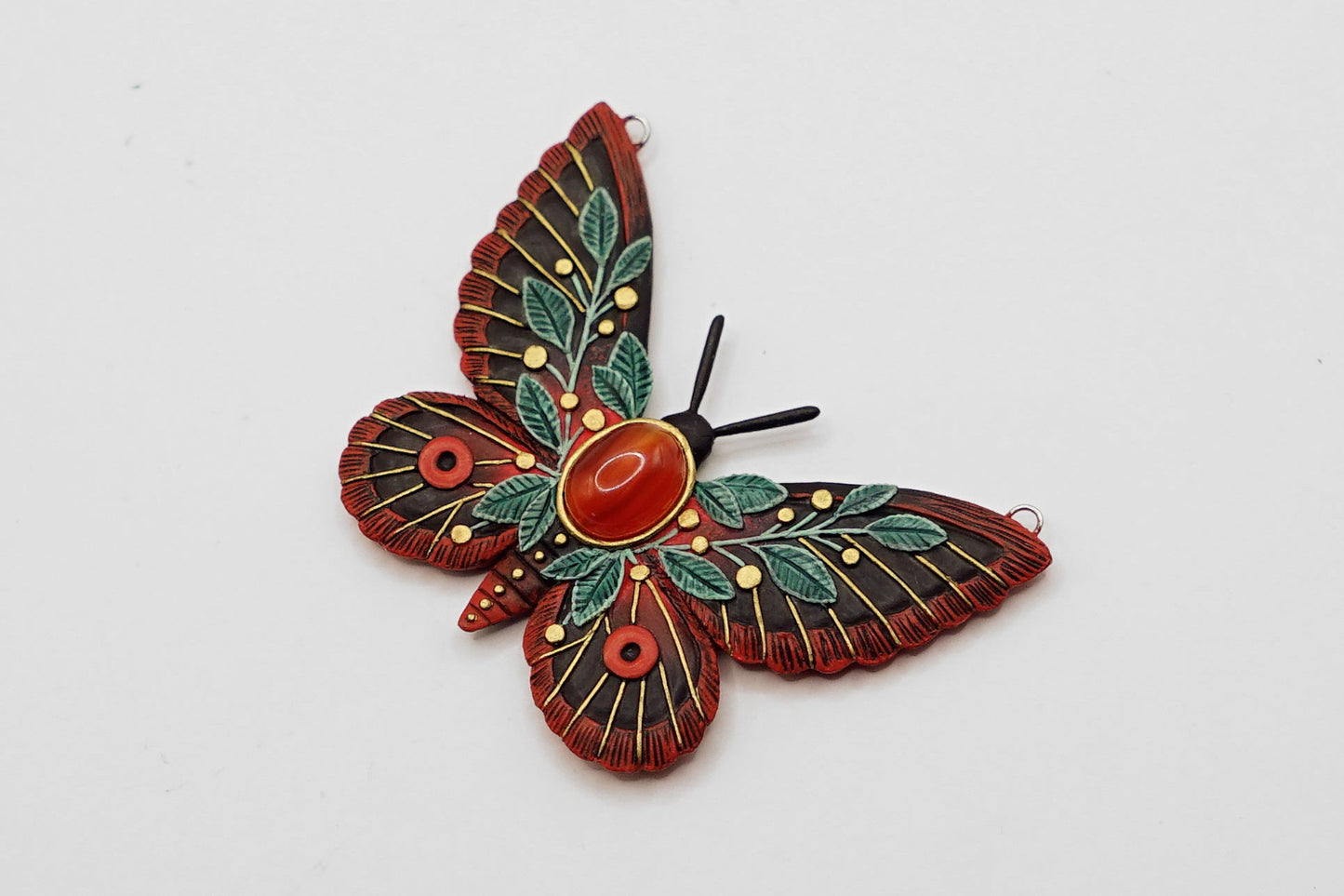Decorative butterfly ornament with red and green details on a white background