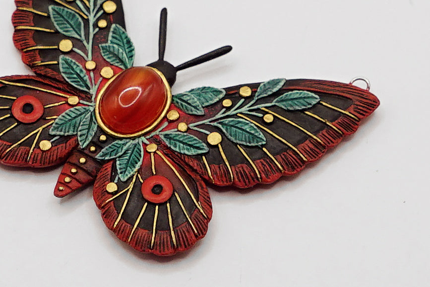 Decorative butterfly ornament with red, green, and gold colors on a white background