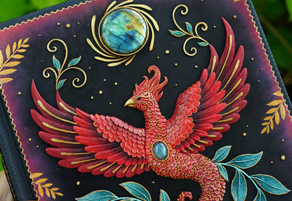 Decorative item with a red phoenix design, turquoise stones, and gold accents on a dark background.