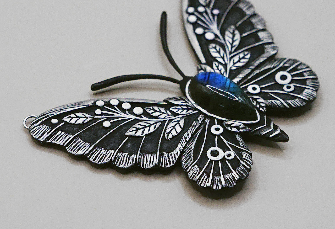 Black and white butterfly-shaped pendant on a light gray background