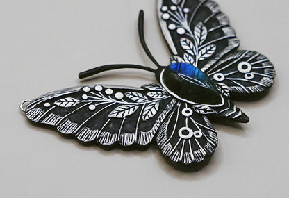 Black and white butterfly-shaped pendant on a light gray background