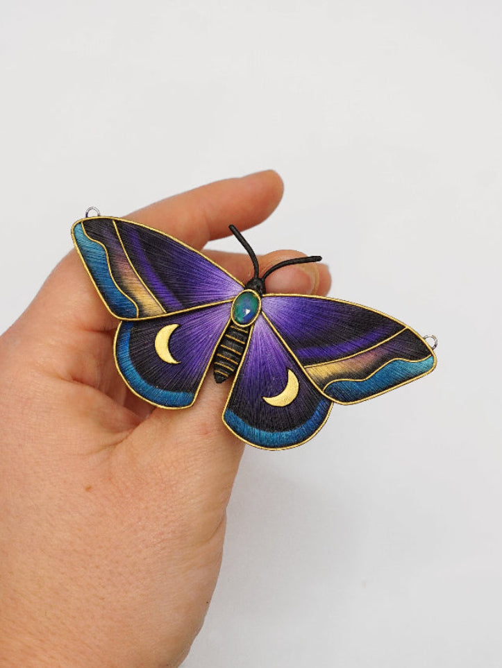 Hand holding a decorative butterfly with purple and blue colors on a white background
